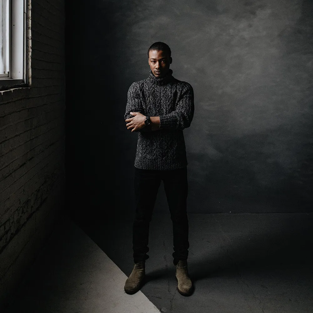 Standing in a dim brick room beside a window, a black Aspect on black leather