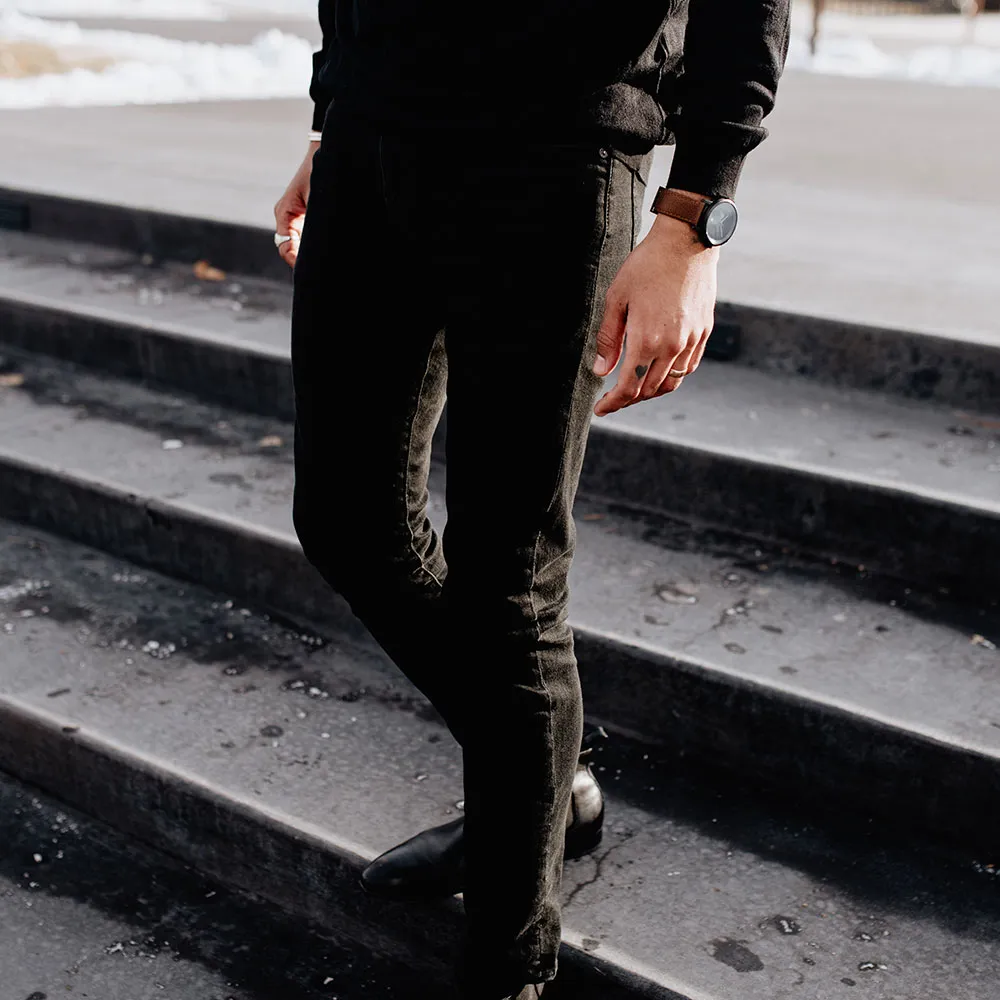 Walking down concrete steps in black trousers, a black Aspect on brown leather
