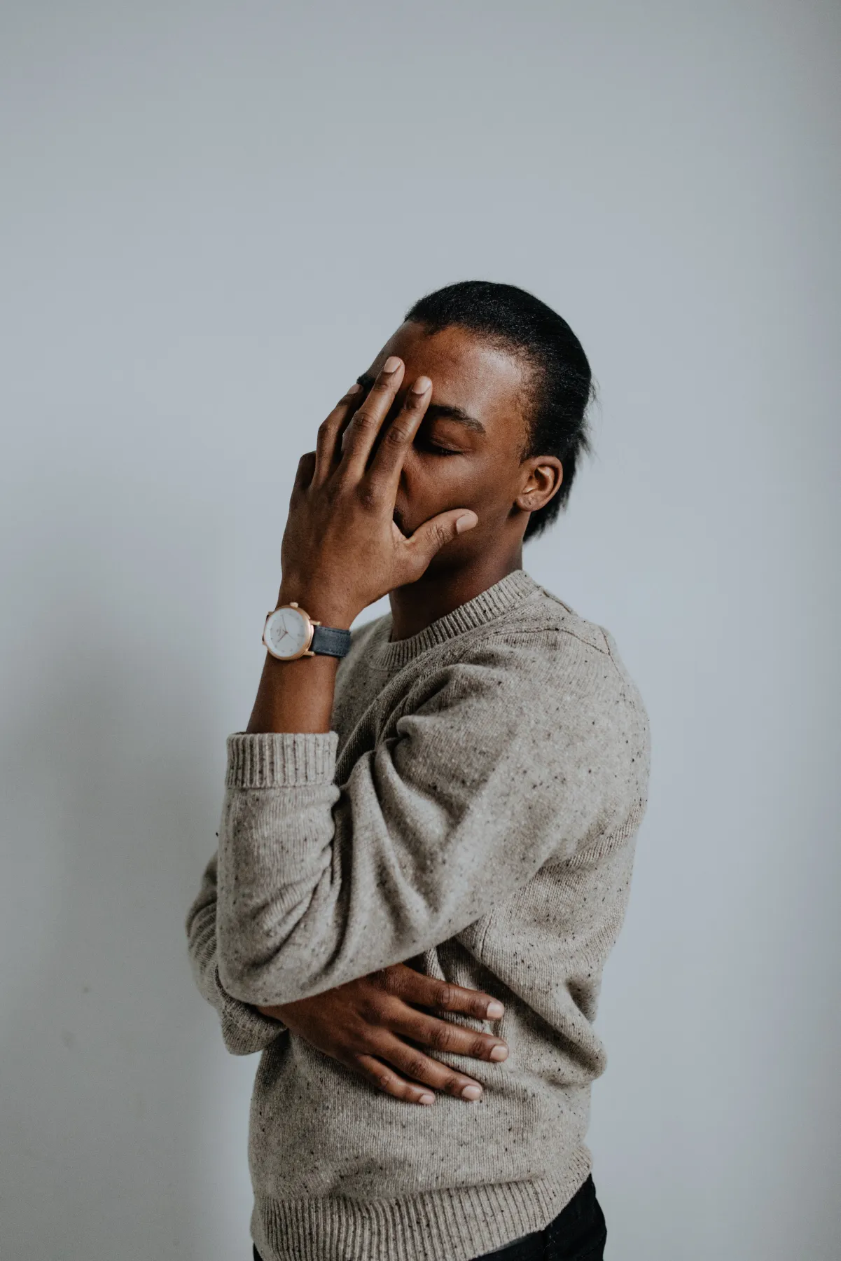 A hand to the face in an oatmeal sweater, a rose gold Aspect on navy leather