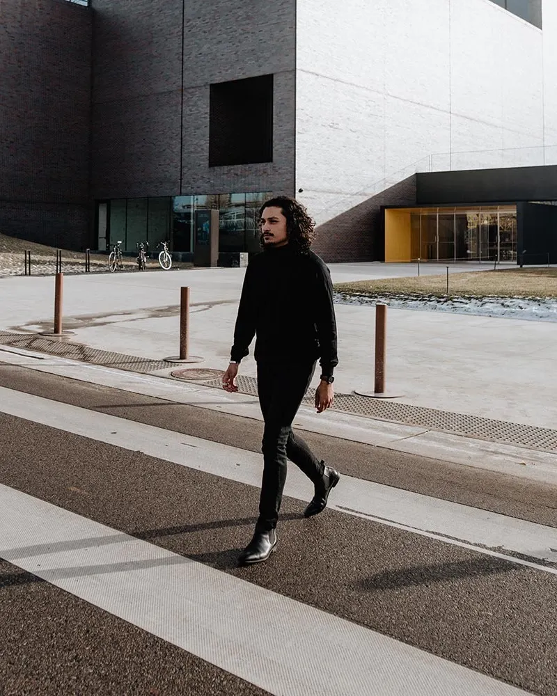 A black Aspect worn crossing the street in black on black